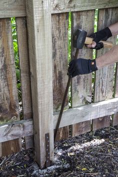 a person using a hammer to attach a wooden fence