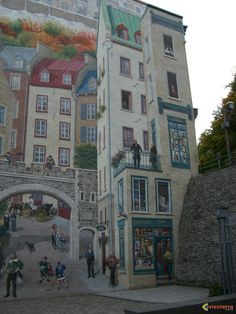 a large mural on the side of a building with people walking around and looking at it