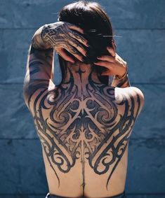 a woman with tattoos on her back covering her eyes