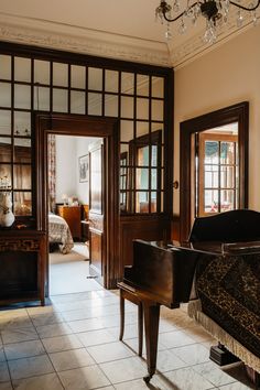 a grand piano sitting in the middle of a room next to two doors and a chandelier