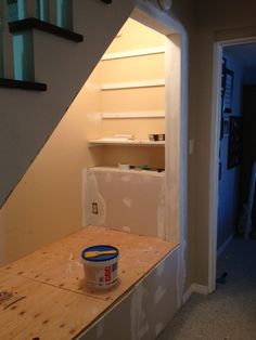 a bucket of paint sitting on top of a wooden table next to a stair case