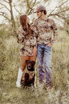 a man and woman standing next to a brown dog in the middle of a field