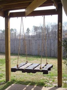 a wooden swing in the middle of a yard