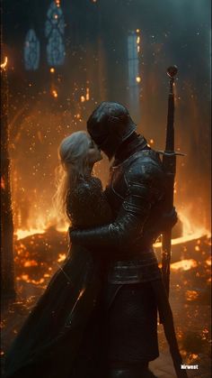 a man and woman dressed in medieval costumes kissing while standing next to each other with fire behind them