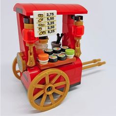 a lego model of a red truck with yellow wheels and some food on the side