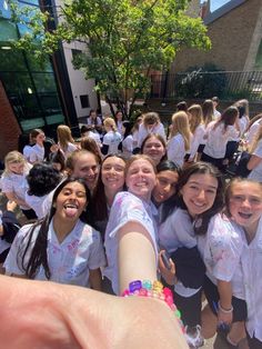 a group of young women standing next to each other in front of a building and pointing at the camera