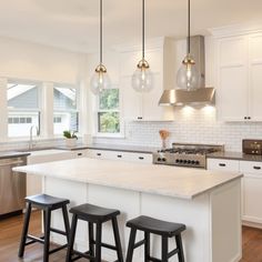 a kitchen with three stools next to an island in the middle of the room