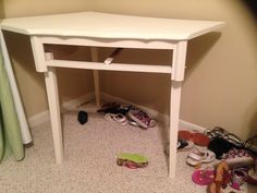 a small white table with shoes underneath it