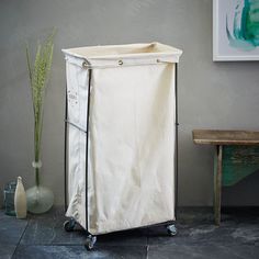 a white laundry hamper sitting on top of a floor next to a wooden table