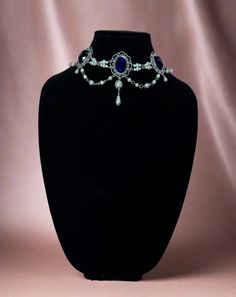 Handcrafted replica period jewelry, made to imitate the style and grandeur of the Tudors. This elegant necklace will complement any renaissance garb, and elevate even the most simple gown into a piece fit for a queen. It is made to order in your choice of gold, silver, or bronze and can be set with resin gemstones of just about any color. Ruby, emerald, sapphire, amethyst and onyx are most popular options.The Marguerite de Navarre features a row of gemstone settings connected with a double line of pearl bead sections. Beautiful swags of metal capped pearls also hang across the bottom. A large pearl and teardrop combo set off the center of the necklace. Tudor Gown, Simple Gowns, Tudor Style, Elegant Necklaces, Accessories Necklace, Pearl Beads, Amethyst, Queen, Gems