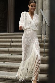 a woman in a white dress is walking down the stairs with her hand on her hip