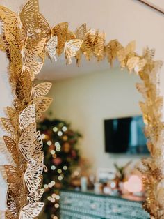 a mirror with gold butterflies on it in front of a christmas tree and a tv