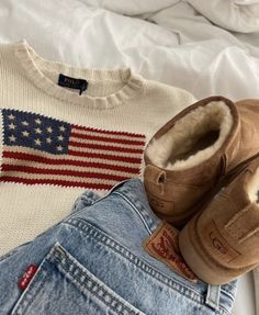 an american flag sweater, jeans and u s slippers are laid out on a bed