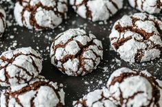 powdered chocolate crinkle cookies on a white plate with the words happily written above them