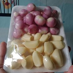 a person holding up a plastic container filled with onions