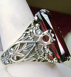 Garnet CZ Sterling Silver RingIntaglio Design#D31 This sterling silver ring is a reproduction of a Victorian filigree antique ring. Inspired by the intricate Victorian designs of the late 1800s and turn of the century, this gorgeous ring is offered in sterling silver. The lovely ring is set with a flawless 7ct Garnet CZ (cubic zirconia) gemstone, by your choice. The baguette shape gemstone is 18mm long by 9mm wide. The ring is 8mm off the finger. The inside of the band is marked 925 for sterling Silver Baguette Cut Crystal Ring For Gift, Formal Garnet Jewelry With Stone Setting, Silver Garnet Wedding Jewelry, Silver Garnet Crystal Ring For Wedding, Wedding Jewelry With Garnet Filigree, Wedding Jewelry With Filigree Garnet, Elegant Oval Crafted Jewelry, Ornate Diamond-cut Ring Jewelry, Ornate Diamond Cut Ring Jewelry