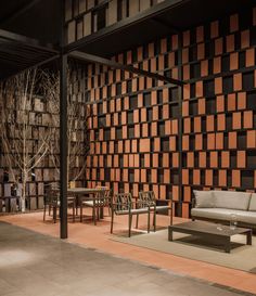 a living room filled with furniture next to a tall wooden wall covered in brown and black squares