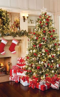 a decorated christmas tree in front of a fire place with stockings on the mantles