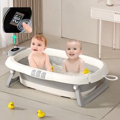 two babies are in the bathtub with rubber ducks