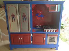 a toy kitchen with spiderman on the door and cupboards painted red, white, and blue