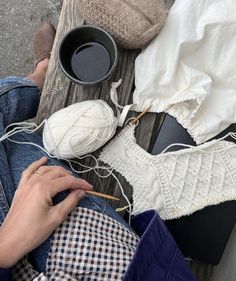 someone is knitting yarn on the ground next to some cups and bowls with yarn in them