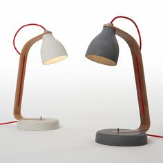 two desk lamps sitting next to each other on top of a white surface with red cords