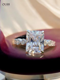 a diamond ring sitting on top of a purple table next to a white cloth covered chair