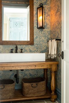 a bathroom with a sink, mirror and basket on the counter in front of it