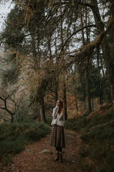 a woman standing on a path in the woods