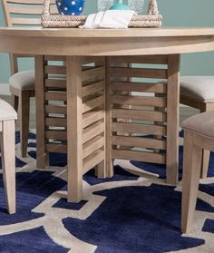 a wooden table with chairs around it on a blue rug in a living room area