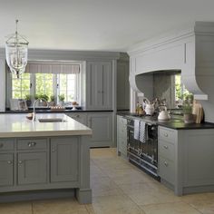 a large kitchen with gray cabinets and white counter tops, an island in the middle