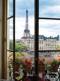 the eiffel tower is seen through an open window with potted flowers in front of it