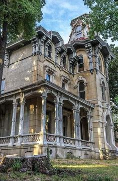 an old building with many windows and balconies on the top floor is surrounded by trees