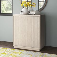 a white vase with yellow flowers sitting on top of a dresser next to a mirror