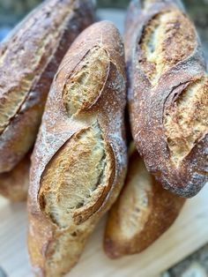 several loaves of bread sitting on top of a wooden cutting board