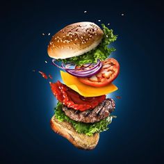 a hamburger flying through the air with lettuce, tomato and onion on it