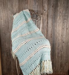 a blue blanket sitting on top of a chair next to a wooden wall in a room