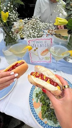 two people sitting at a table eating hotdogs with mustard and ketchup