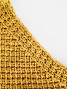 a close up of a knitted piece of cloth on a white surface with no background