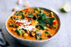 a white bowl filled with soup and garnished with fresh herbs, sour cream and cilantro