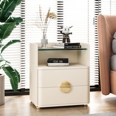 a white nightstand with books and plants on top