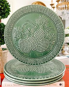 a stack of green plates sitting on top of a table next to a potted plant