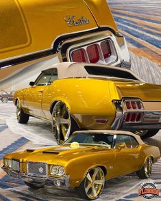 two yellow muscle cars parked next to each other