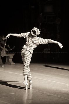 a woman in striped pajamas is doing a dance move on the stage with her arms outstretched