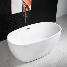 a large white bath tub sitting on top of a tiled floor next to a black wall