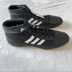 a pair of black and white adidas shoes on top of a bed covered in sheets