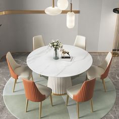 a white table with four chairs around it and a vase filled with flowers on top