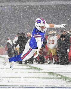 a football player is in mid air after catching the ball during a snow storm with people watching