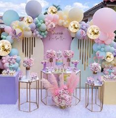 a pink and blue party with balloons, flowers, and desserts on the table