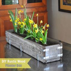 a wooden planter with yellow flowers in it